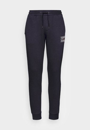 Black sweatpants made of soft fabric feature an elastic waistband with a drawstring, tapered legs, and a white logo print on the hip.