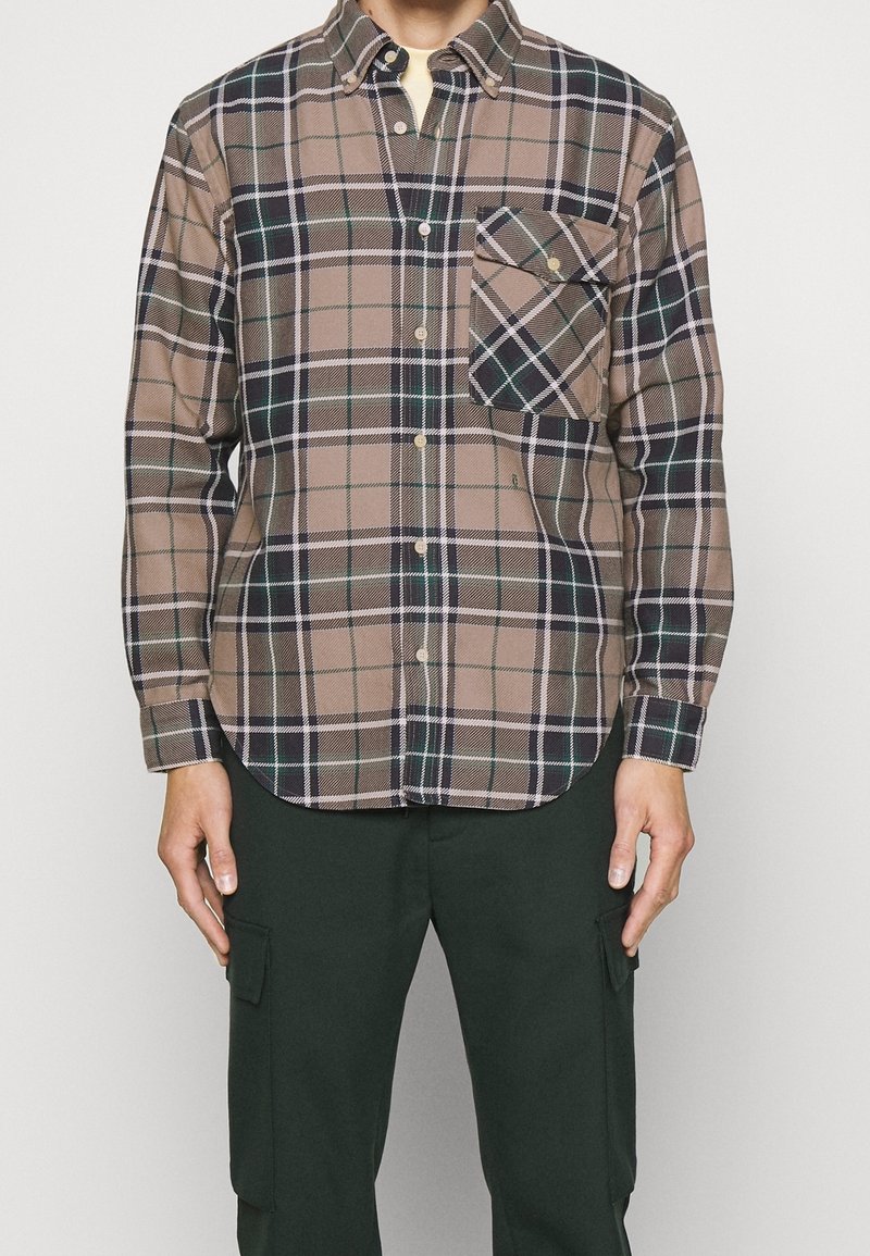 Ruskea ja musta ruudullinen napitettava paita, jossa vihreät yksityiskohdat, rintatasku, kauluksellinen pääntie ja pitkät hihat. Valmistettu pehmeästä kankaasta.