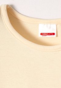 Tela color crema con cuello redondo y detalles cosidos, que presenta una etiqueta que dice "THERMOLACTYL by DAMART."