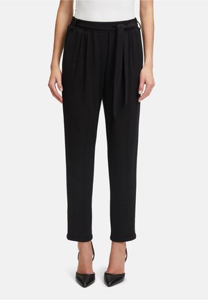 Pantaloni neri affusolati con una texture morbida, dotati di vita legata e risvolti, abbinati a tacchi neri a punta.