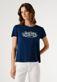 Μπλε ναυτικό βαμβακερό t-shirt με κοντά μανίκια, που διαθέτει floral γραφικό και κείμενο "London" στο μπροστινό μέρος. Καθαρός, casual σχεδιασμός με χαλαρή εφαρμογή.