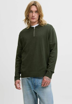 Mörkgrön tröja med dragkedja vid kragen, ribbad mudd och nederkant. Matchad med ljusblå denimjeans med subtil blekning.