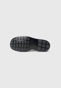 Black rubber shoe sole with a textured pattern of squares and rectangles, featuring a smooth finish and slight curvature at the toe area.