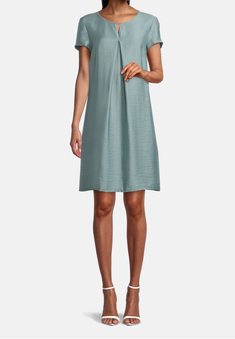 Un vestido de manga corta, hasta la rodilla, en un tono verde azulado suave, con un pequeño escote en forma de ojal y un detalle de pliegues en la parte delantera. Tela suave y ligeramente brillante.