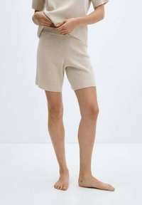Beige knit lounge set featuring a short-sleeve top and mid-thigh shorts. The fabric has a smooth texture and a fitted design.