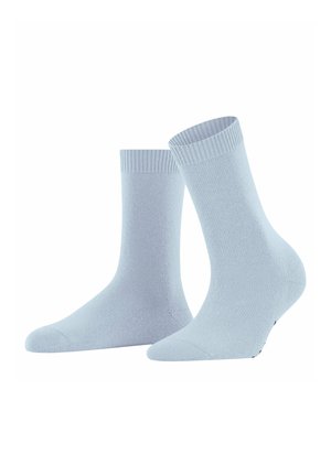 Une paire de chaussettes bleu clair de type crew avec des poignets côtelés, l'une debout et l'autre inclinée sur le côté, sur fond blanc.
