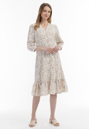 Rochie midi florală cu decolteu în v formă, mâneci trei sferturi și tiv evazat cu volane. Țesătura ușoară este împodobită cu mici modele florale roșii și verzi.