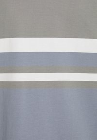 Strisce orizzontali in toni smorzati di grigio, bianco e blu su una superficie di tessuto.