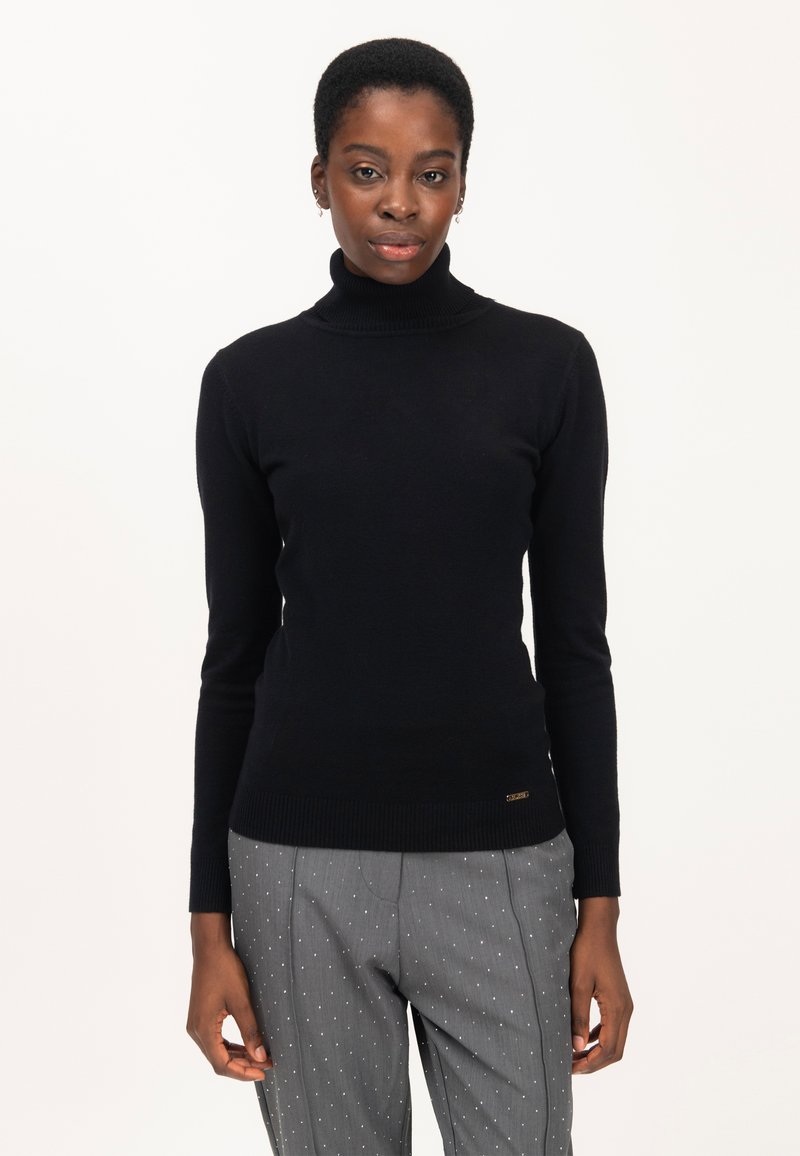 Maglione a collo alto nero in tessuto a maglia, design aderente, maniche lunghe, orlo a coste sottile, abbinato a pantaloni grigi a righe sottili con punti bianchi.