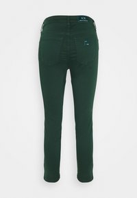 Mörkgröna bomullsjeans med en figurnära passform, femfickorsdesign och märkta lappar vid midjan och bakfickan. Slät textur.