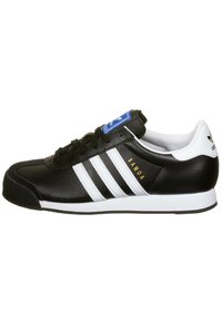 Černá kožená teniska s bílým vzorem tří pruhů, gumovou špičkou, zlatým nápisem "Samoa" a modrým štítkem na jazyku. Plochá bílá podrážka.