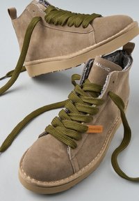 Zapatillas de ante beige de caña alta con gruesos cordones verde oliva y forro de pelo, con suela de goma y etiqueta de cuero con marca.