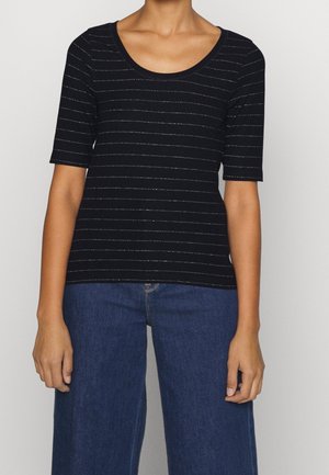 Zwarte geribbelde top met korte mouwen, voorzien van metallic zilveren horizontale strepen en een ronde halslijn, gecombineerd met wijde blauwe jeans.