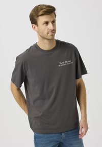 Szary bawełniany t-shirt z okrągłym dekoltem. Na lewej stronie biały nadruk "Porte d'Auteuil" oraz współrzędne. Krótkie rękawy.