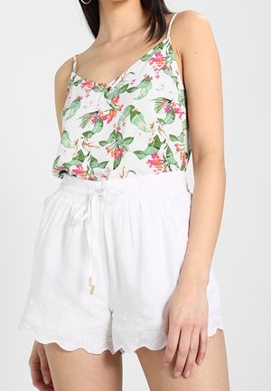 Bloemenprint top met groene bladeren en roze bloemen, gecombineerd met witte shorts met een golfrand en geborduurde accenten.