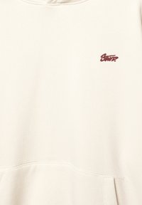Kremowy hoodie z przednią kieszenią, prążkowanymi mankietami i małym bordowym logo. Wykonany z miękkiego, fakturowanego materiału.