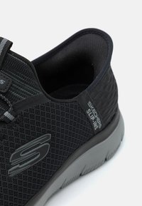 Pantofii slip-on din plasă negri, cu un toc texturat, talpă exterioară gri și un accent cu logo. Au un design flexibil și un interior căptușit.