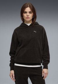 Felpa con cappuccio nera in corduroy, dotata di tasca a marsupio e trama a coste, caratterizzata da un piccolo logo Puma bianco sul lato sinistro del petto.