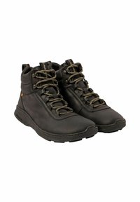 Un par de botas altas de cuero negro con cordones verdes y suelas gruesas y texturizadas, inclinadas ligeramente a la derecha sobre un fondo blanco.
