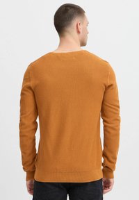 Teksturowany pomarańczowy sweter z długimi rękawami, okrągłym dekoltem i ściągaczami. Zaprojektowany z wzorem w kompozyt i w luźnym kroju.