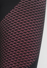 Leggings neri con una superficie texturizzata caratterizzata da un motivo a griglia di diamanti rosa, che aumenta l'interesse visivo e la profondità.