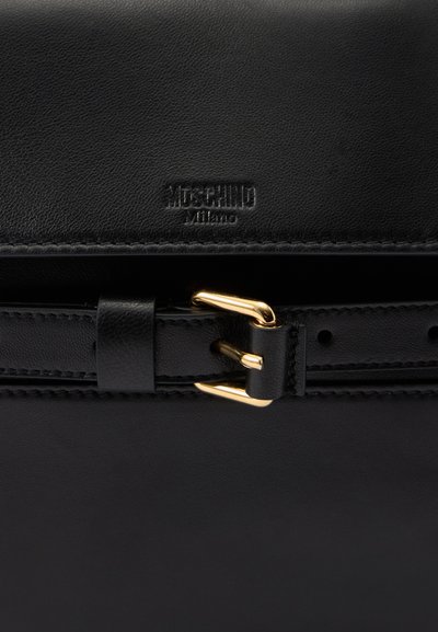 Sac en cuir noir avec une surface texturée, doté d'une boucle en métal doré et d'une marque en relief. Design épuré et minimaliste avec des détails de couture.