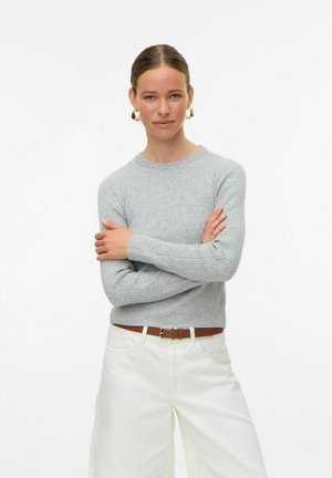 Ljusgrå ribbad tröja med rund halsringning och långa ärmar, bärs med vita högmidjade shorts och ett brunt bälte.