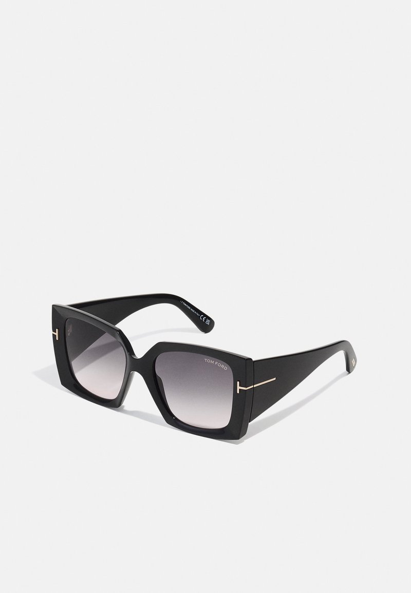 Occhiali da sole neri Tom Ford con lenti quadrate sovradimensionate, tonalità sfumata e dettagli in logo dorato sulle tempie. Finitura opaca, design elegante.