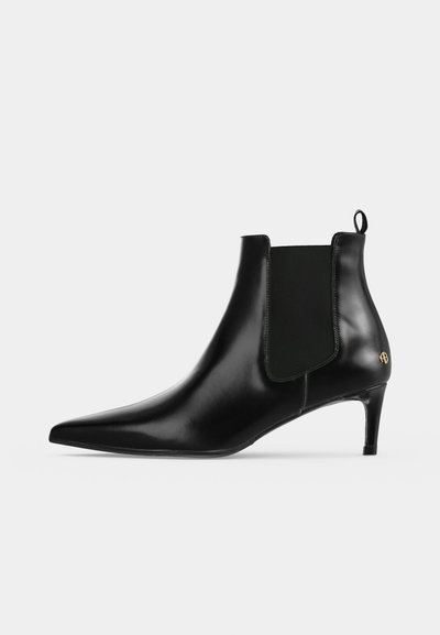Bottine noire en cuir à bout pointu, avec empiècement latéral élastique, tirette, petit emblème doré et talon fin.