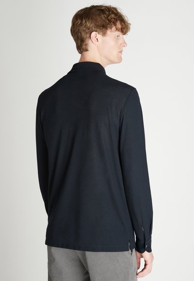 Langärmliges navy Hemd aus weichem Stoff, mit klassischem Kragen, seitlichen Schlitzen am Saum und geknöpften Manschetten. Rückansicht dargestellt.