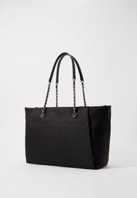 Sac fourre-tout noir en tissu lisse, avec deux poignées lisses et des accents en chaîne. Le sac a une forme rectangulaire structurée.