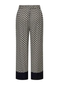 Pantalons large à motifs en crème et bleu marine, arborant un design géométrique et une taille élastique. Les poignets sont en tissu bleu marine uni.
