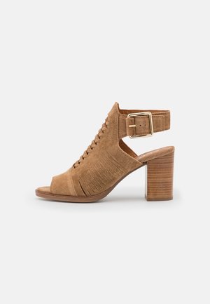 Sandale à talon en daim camel avec bout ouvert, découpes latérales, panneaux texturés et bride à boucle. Dotée d'un talon bloc en bois.