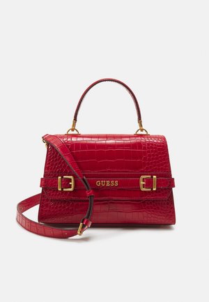Sac à main en cuir embossé crocodile rouge avec poignée supérieure, bandoulière réglable, boucles dorées et logo GUESS sur le rabat avant.