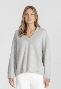 Jasnoszary sweter z dzianiny z dekoltem w kształcie V, z prążkowanymi mankietami i dołem. Luźny krój i miękka tekstura, zaprojektowany z myślą o komforcie i noszeniu na cebulkę.