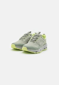 Chaussures de sport gris clair avec un dessus texturé, des accents réfléchissants et des détails jaune fluo. Dotées d'une semelle rembourrée et d'un design à lacets.