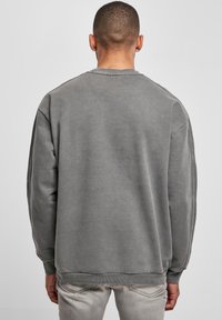 Sudadera gris de manga larga, cuello redondo y puños y dobladillo de canalé. Textura suave y lisa con detalles de costura mínimos.