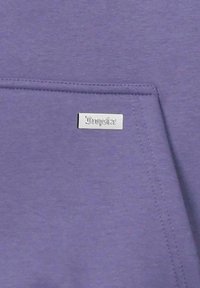 Lila Sweatshirt-Stoff mit einer weichen Textur. Verfügt über ein kleines, silbernes Etikett mit der Prägung "Dropsize", nahe einer Taschennäht.
