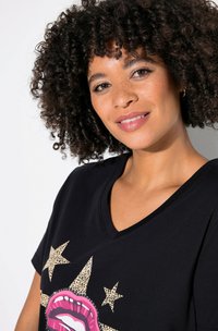 Czarny t-shirt v-neck z różowym grafikiem ust i gwiazdkami w panterkę. Miękka tkanina, luźny krój i krótkie rękawy.