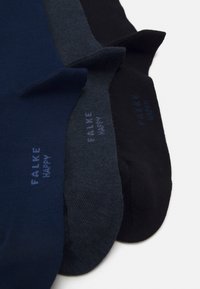 Tres pares de calcetines en azul marino, azul oscuro y negro, con una textura acanalada y el nombre de la marca "FALKE HAPPY" impreso en azul.