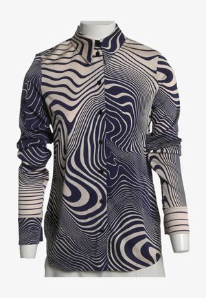 Langærmet skjorte med knapper med marineblåt og beige bølget striped mønster, der skaber en optisk illusionseffekt på stoffet.