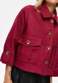 Bordeaux cropped jack gemaakt van gestructureerde stof, met grote voorkruiszakken, ronde bruine knoppen en een omgeslagen kraag.