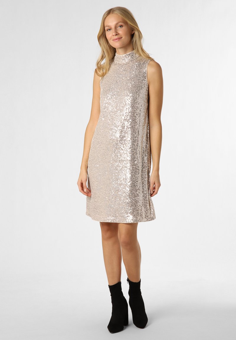 Sukienka bez rękawów o wysokim dekolcie, pokryta metalicznymi różowymi cekinami, w kształcie A z długością do kolan, zestawiona z czarnymi botkami do kostki.