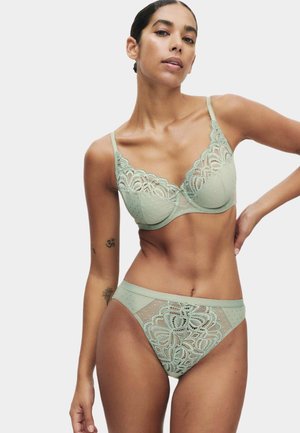 Sujetador de encaje verde claro y braga de talle alto a juego con patrones de lunares y detalles de encaje floral. Tejido suave y texturizado con tirantes ajustables.