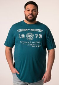 Teal tričko s krátkým rukávem se bílým nápisem: "TROUT TROPHY 1978," grafikou s outdoorovou tematikou a uvolněným střihem.