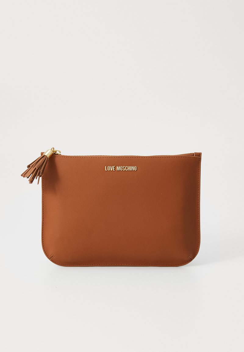 Brūna mākslīgās ādas rokas soma ar rāvējslēdzēju, kurai ir zelta logotips un dekoratīvs pompons uz rāvējslēdzēja. Gluda tekstūra.