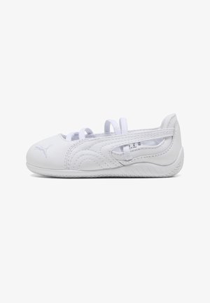 Biały but sportowy z cienką podeszwą, bocznymi wycięciami, białymi sznurówkami, logo Puma na nosku oraz widocznymi detalami przeszyć, przedstawiony z profilu.