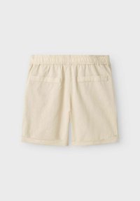 Shorts en lin beige avec une taille élastique, deux poches arrière et des ourlets roulés. Le tissu a une finition texturée.