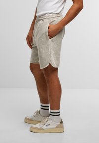 Shorts gris clair en velours doux, avec une taille élastique, deux poches latérales et un ourlet arrondi.