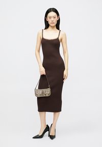 Vestido midi canelado castanho com alças finas, apresentando um tecido texturizado. Combinado com uma pequena mala cinzenta e sapatos pretos de salto alto.